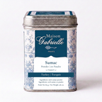 A tin of Maison Gabrielle Sumac Powder (Turkey/Turquie) on a clean white background. The product is packaged in a square metal tin with a silver lid and a label featuring a blue and white toile pattern with a dark blue central panel.